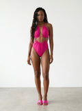 Woman wearing a magenta pink cut-out one-piece swimsuit, studio photography, front view