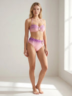 Driftly pink leopard print gradient halter swimsuit with high-waisted, ruched styling and gold hardware, in a minimalist studio setting with soft window light.
