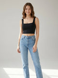 Driftly women's black polyester cropped tank top with a slash neckline, styled with white wide-leg trousers in a minimalist studio setting.