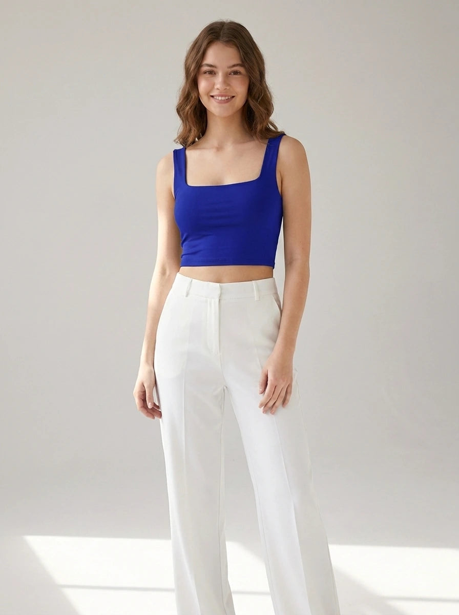 Driftly women's royal blue polyester cropped tank top with a slash neckline, styled with white wide-leg trousers in a minimalist studio setting.