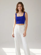 Driftly women's royal blue polyester cropped tank top with a slash neckline, styled with white wide-leg trousers in a minimalist studio setting.