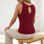 Driftly women's burgundy sleeveless V-neck tank top, styled with beige linen trousers, seated in a bright interior.