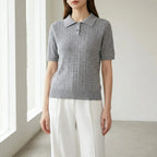 Driftly women's gray cotton polo t-shirt, styled with white wide-leg trousers in a minimalist studio setting.