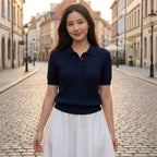 Driftly women's navy cotton polo t-shirt, styled with a white midi skirt on a European street at golden hour.
