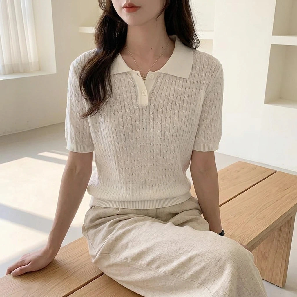 Driftly women's white cotton polo t-shirt, styled with beige linen trousers, seated in a bright interior.