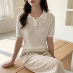 Driftly women's white cotton polo t-shirt, styled with beige linen trousers, seated in a bright interior.