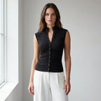 Driftly women's black ribbed ruched button front top, styled with white wide-leg trousers in a minimalist studio setting.
