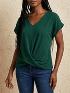 Woman wearing a green v-neck twist front short sleeve top with jeans