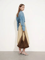 Woman carrying a brown suede slouchy shoulder tote bag, side view in a studio setting
