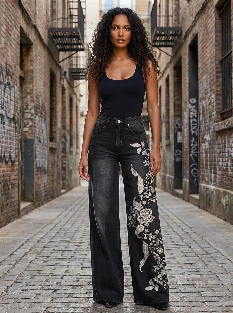 Woman in black floral print wide-leg trousers standing in an urban alley