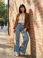 Woman wearing blue bohemian print wide-leg trousers against a brick wall