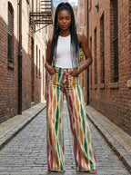 Woman in multicolor striped bohemian wide-leg trousers standing in a brick alley