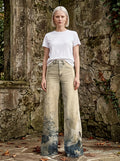 Woman wearing cream-beige tie-dye ombre wide-leg trousers against ancient stone ruins