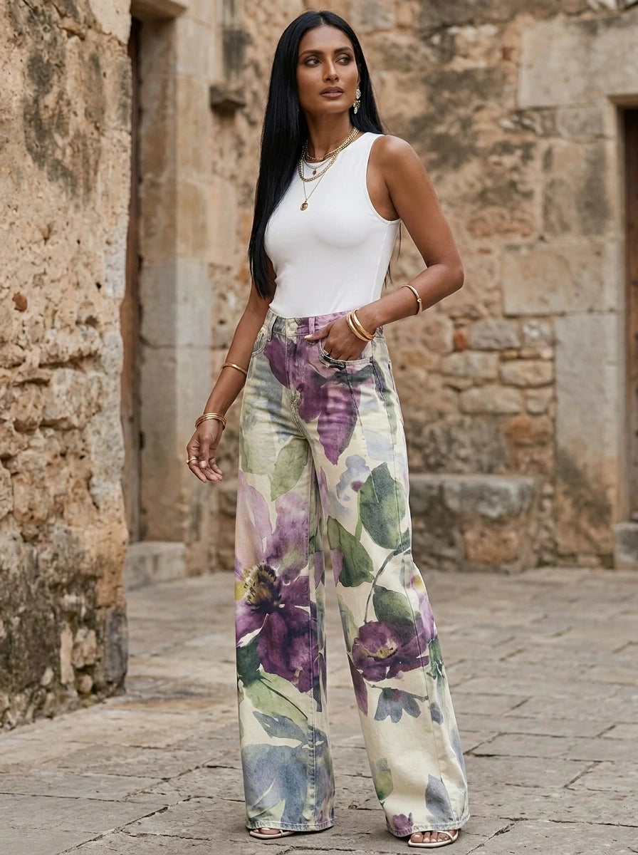 Woman in purple floral print wide-leg trousers standing in a stone courtyard