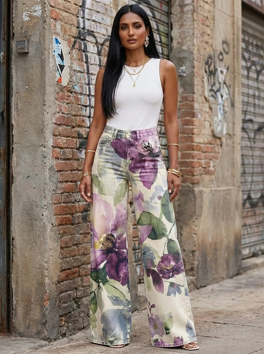 Woman in purple floral print wide-leg trousers standing against an urban wall