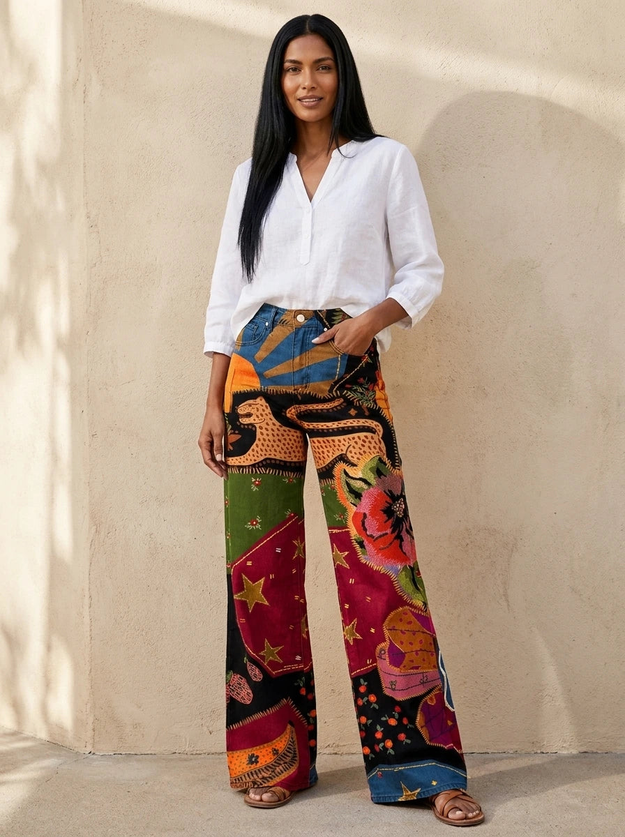 Woman wearing red boho style wide-leg patterned trousers, standing against an urban wall