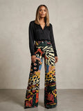 Woman wearing black chic wide-leg trousers with an animal-print pattern, studio setting
