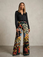 Woman wearing black chic wide-leg trousers with an animal-print pattern, studio setting