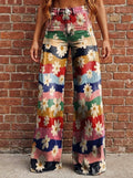 Woman wearing multicolor floral chic wide leg trousers against a brick wall