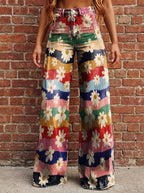 Woman wearing multicolor floral chic wide leg trousers against a brick wall