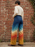Woman wearing multicolored vintage zigzag high-waisted wide leg trousers against a brick wall