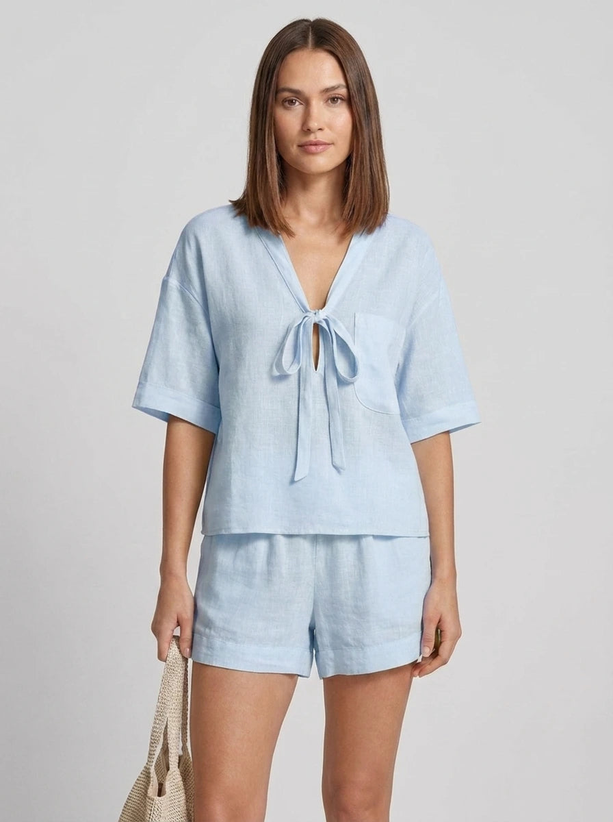 Woman wearing a light blue casual two-piece set with short collar in a studio setting
