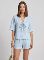 Woman wearing a light blue casual two-piece set with short collar in a studio setting