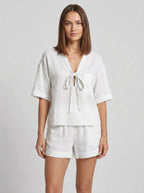 Woman wearing a white casual two-piece set with short collar in a studio setting