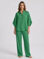 Woman wearing a green linen-style two-piece set, relaxed button-front top and wide-leg trousers, studio shot
