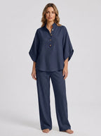 Woman wearing a navy blue linen-style two-piece set, relaxed button-front top and wide-leg trousers, studio shot