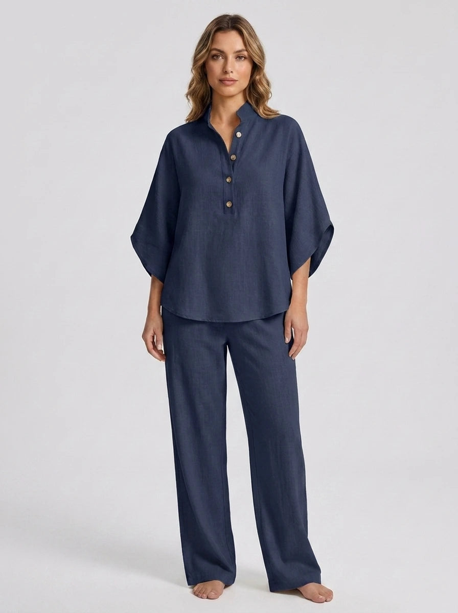 Woman wearing a navy blue linen-style two-piece set, relaxed button-front top and wide-leg trousers, studio shot