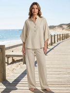 Woman wearing a sand beige linen-style two-piece set on the beach, relaxed casual summer outfit