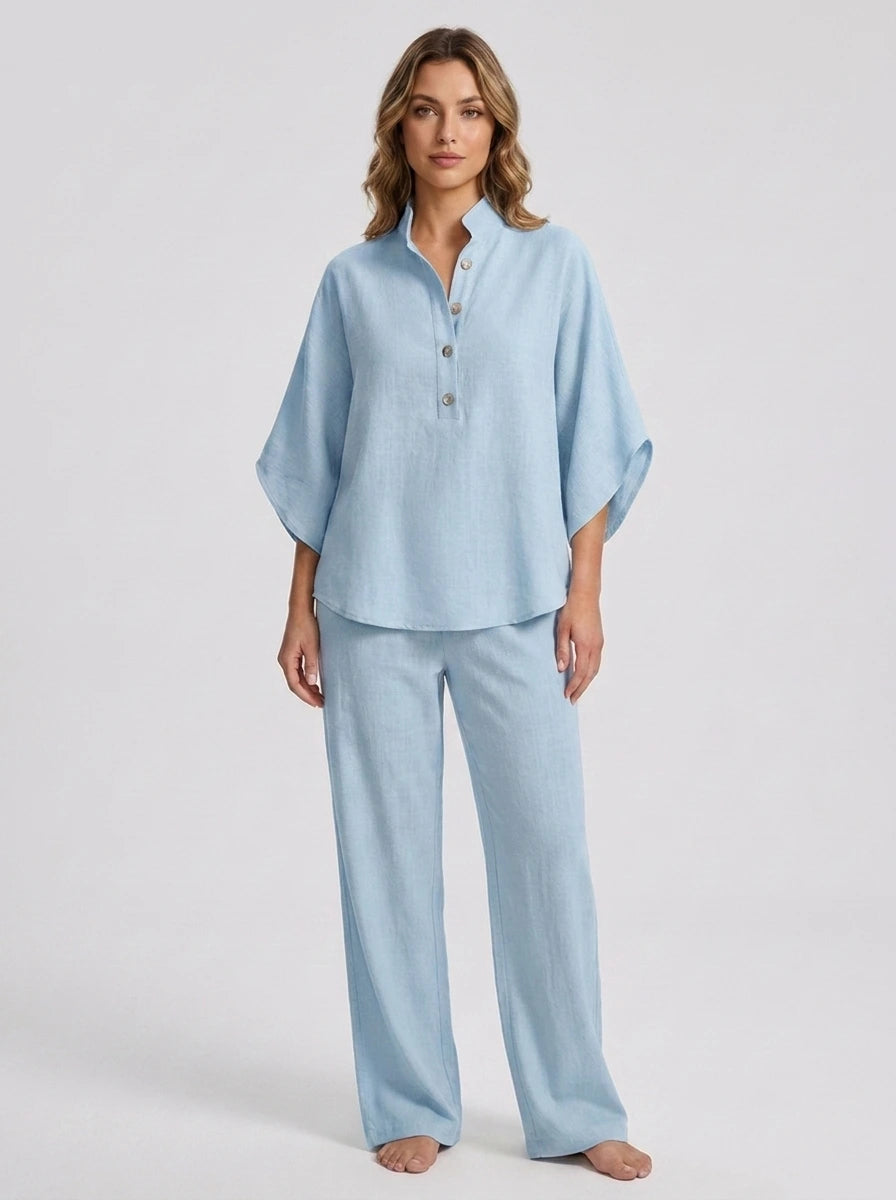 Woman wearing a sky blue linen-style two-piece set, relaxed button-front top and wide-leg trousers, studio shot
