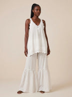 Woman wearing a white eyelash lace cami top and wide-leg pants two-piece set on a city street
