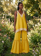 Woman wearing a yellow eyelash lace cami top and wide-leg pants two-piece set in a garden