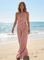 Woman wearing a pink one-shoulder ruched cutout cami top and wide-leg pants two-piece set on a sunny beach