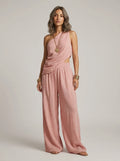 Woman wearing a pink one-shoulder ruched cutout cami top and wide-leg pants two-piece set in a studio setting