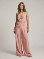 Woman wearing a pink one-shoulder ruched cutout cami top and wide-leg pants two-piece set in a studio setting