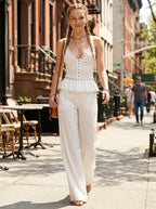Woman wearing a white ribbed cami crop top and matching wide-leg pants two-piece set on a sunny city street