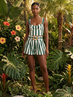 Woman wearing a green striped smocked tank top and bubble shorts two-piece set in a tropical garden