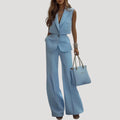 Woman wearing a light blue sleeveless blazer and wide-leg trouser set in a studio setting