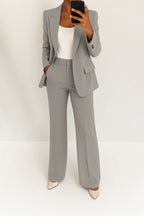 Woman wearing a grey wide-leg button-down blazer and trouser set in a studio setting