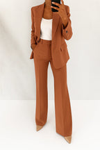 Woman wearing a brown wide-leg button-down blazer and trouser set in a studio setting