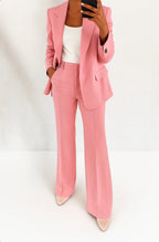 Woman wearing a pink wide-leg button-down blazer and trouser set in a studio setting