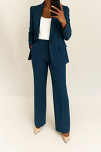 Woman wearing a navy blue wide-leg button-down blazer and trouser set in a studio setting