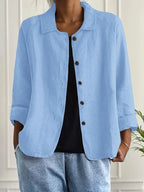 Woman wearing a light blue collared button-front long sleeve blazer in a studio setting