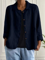Woman wearing a navy blue collared button-front long sleeve blazer in a studio setting