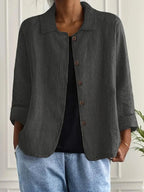 Woman wearing a dark grey collared button-front long sleeve blazer in a studio setting
