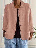 Woman wearing a pink collared button-front long sleeve blazer in a studio setting