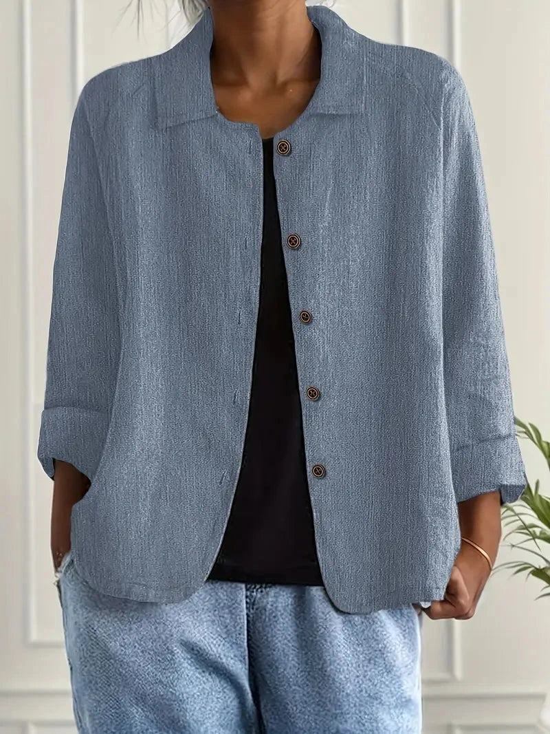 Woman wearing a blue collared button-front long sleeve blazer in a studio setting